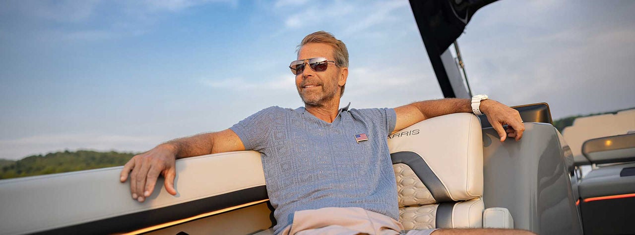 A man relaxing on this Harris Pontoon with a sunny sky