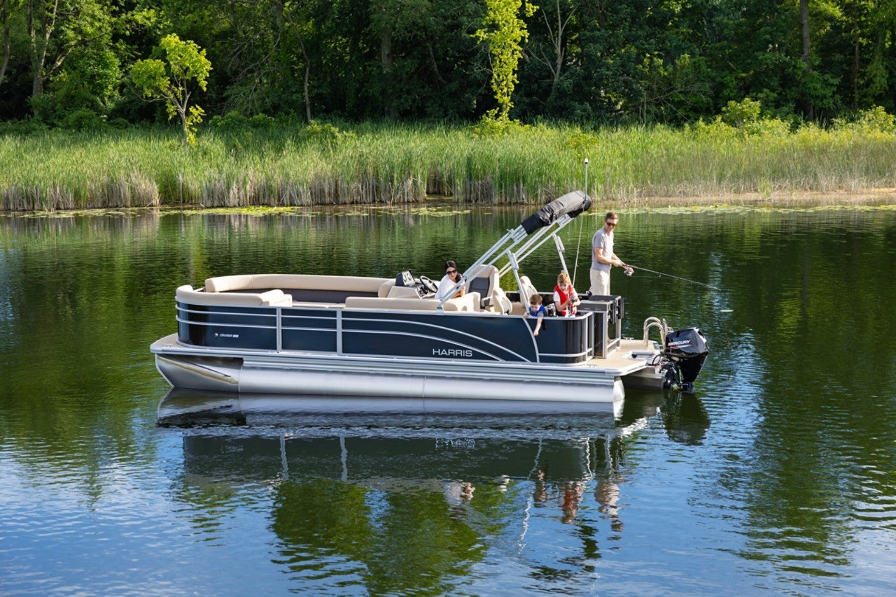 Mom and Dad with two young sons fishing off the back of the Harris fishing pontoon boat in a beautiful cove.