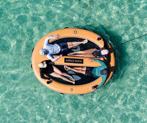 An orange egg shaped chair floating on blue shallow water